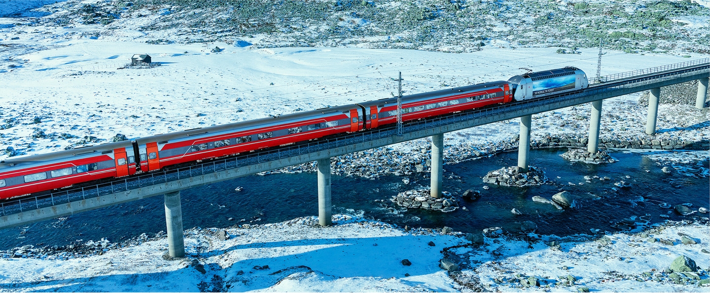 Et tog som kjører over en bro på vinterstid.